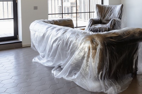 Sofa und Sessel unter Abdeckfolie, bereit zum Streichen