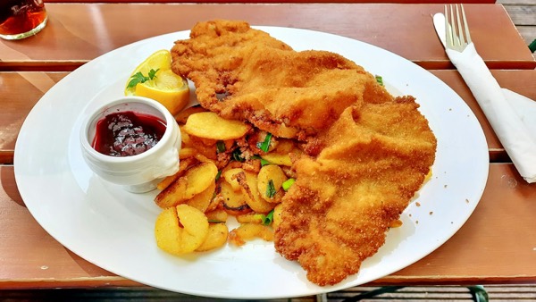 Paniertes Schnitzel mit Bratkartoffeln, Zitrone und Preiselbeeren