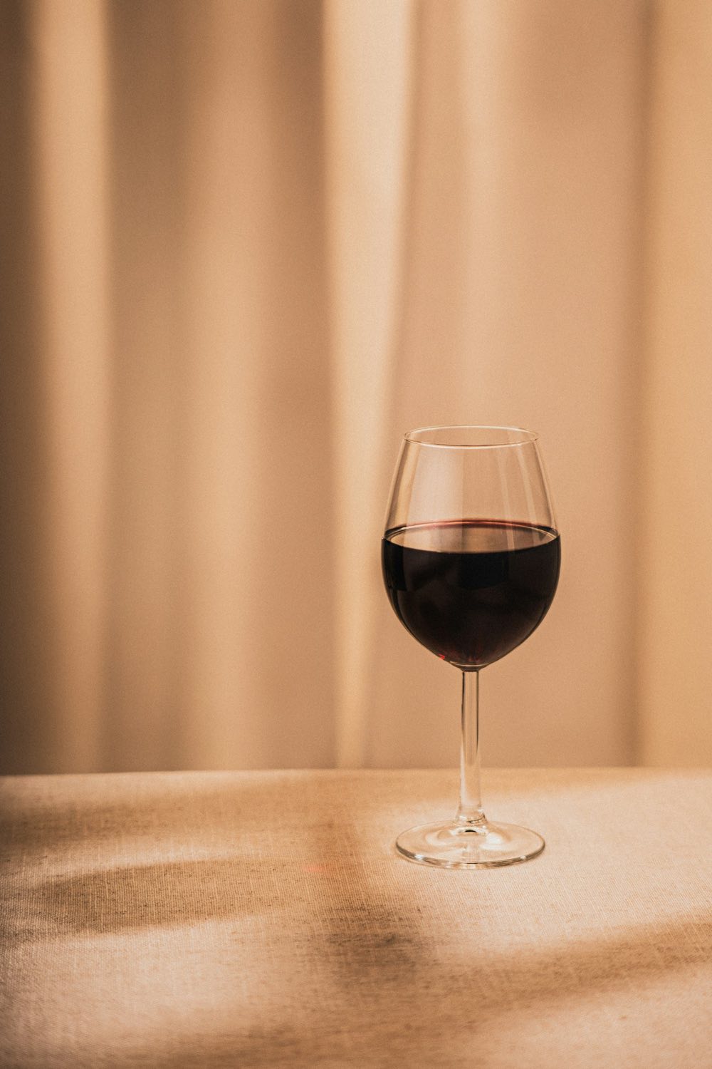 Glas Rotwein auf einem Tisch im Gegenlicht